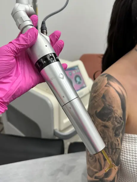 A woman is holding an electric tattoo machine.